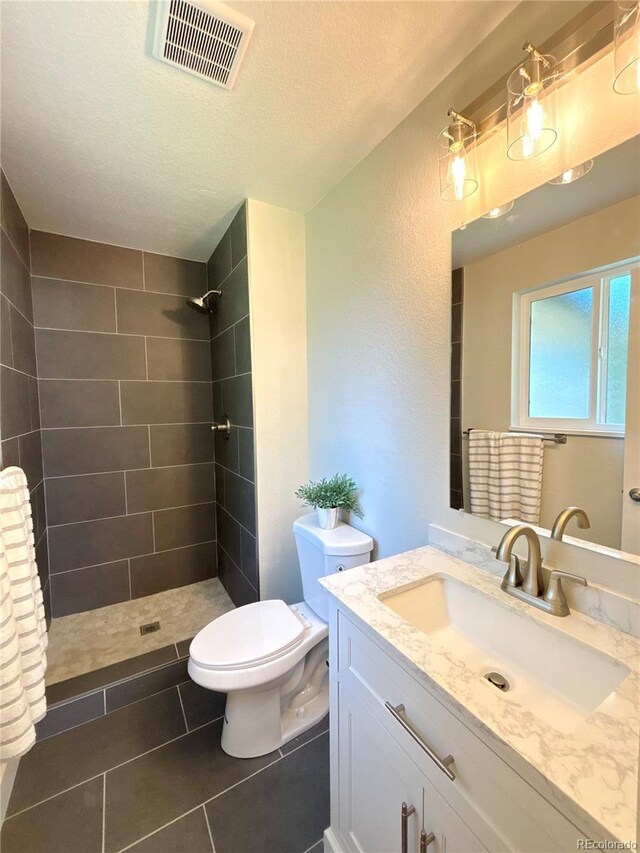 6484 S Datura St, Littleton, CO 80120 - bathroom with tiled shower, vanity, a textured ceiling, and tile patterned floors