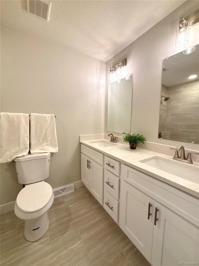 6484 S Datura St, Littleton, CO 80120 - bathroom featuring double vanity, tiled shower, a textured ceiling, and a textured wall
