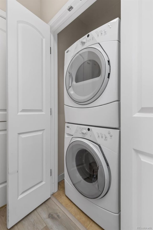 clothes washing area featuring light wood-type flooring and stacked washing maching and dryer