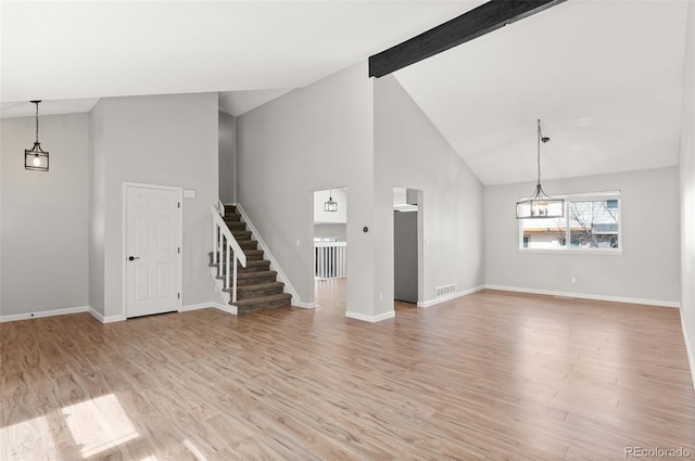 unfurnished living room featuring stairs, beamed ceiling, baseboards, and light wood-type flooring