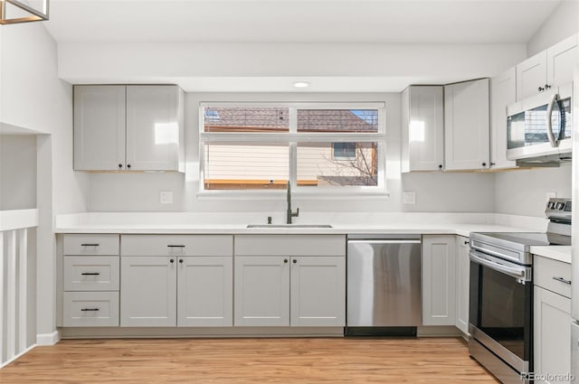 kitchen featuring a sink, light countertops, light wood finished floors, and stainless steel appliances