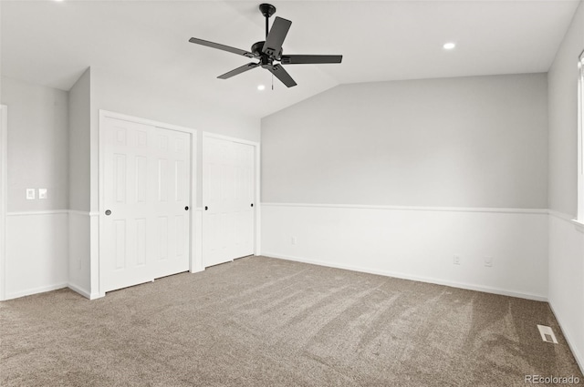 unfurnished bedroom featuring visible vents, recessed lighting, vaulted ceiling, carpet flooring, and two closets