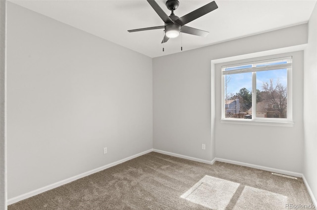 carpeted spare room featuring baseboards and ceiling fan