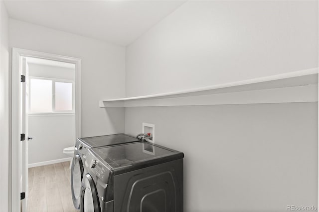 washroom featuring baseboards, light wood-style flooring, laundry area, and washing machine and clothes dryer