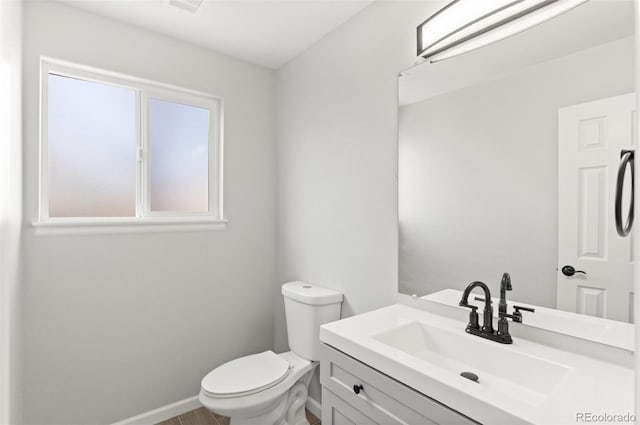 half bath featuring toilet, vanity, and baseboards