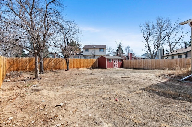 view of yard featuring a fenced backyard, a storage unit, and an outdoor structure