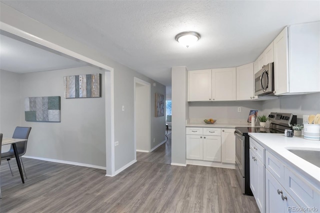 kitchen featuring hardwood / wood-style flooring, white cabinetry, a textured ceiling, and appliances with stainless steel finishes