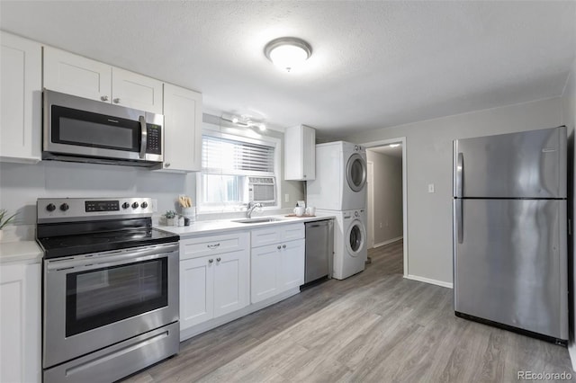 kitchen with sink, white cabinets, stacked washing maching and dryer, and appliances with stainless steel finishes