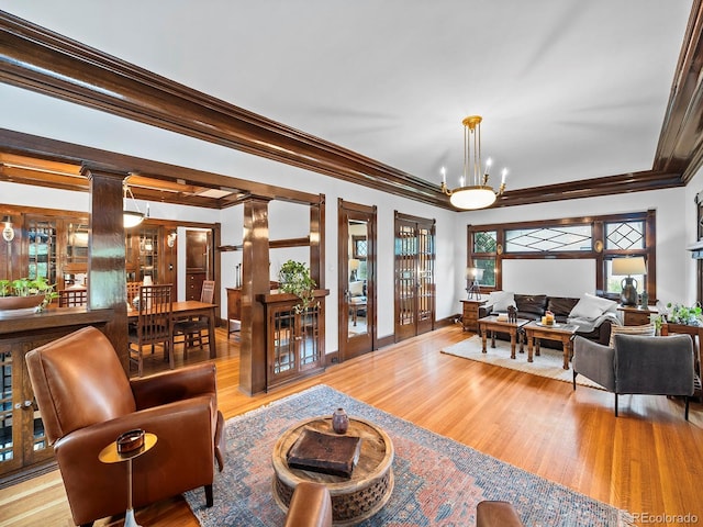 living room featuring ornamental molding, a chandelier, and light hardwood / wood-style flooring