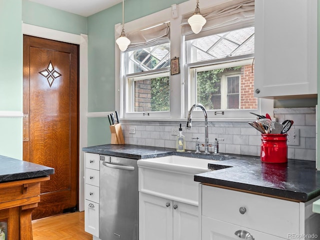 kitchen featuring backsplash, decorative light fixtures, stainless steel dishwasher, and white cabinets