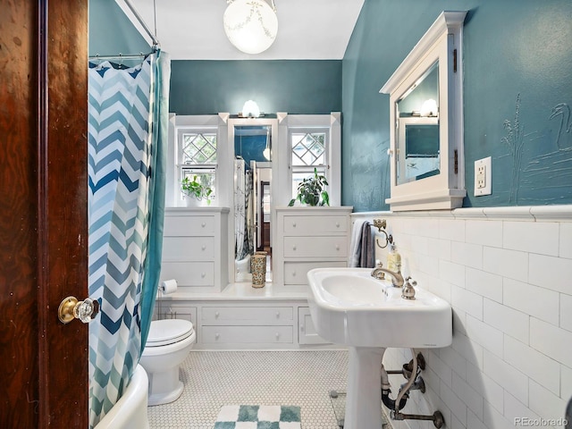 bathroom featuring shower / bath combo, tile walls, and toilet