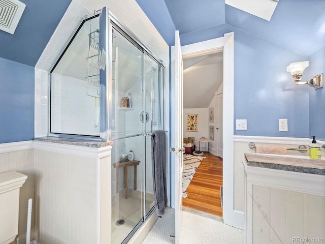 bathroom featuring vaulted ceiling, hardwood / wood-style floors, vanity, and a shower with shower door