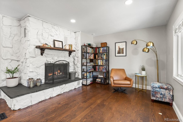 living area featuring a healthy amount of sunlight, dark hardwood / wood-style floors, and a fireplace