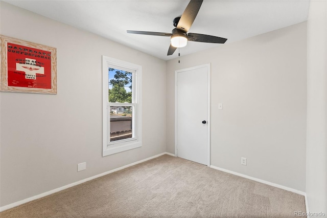 carpeted spare room featuring ceiling fan