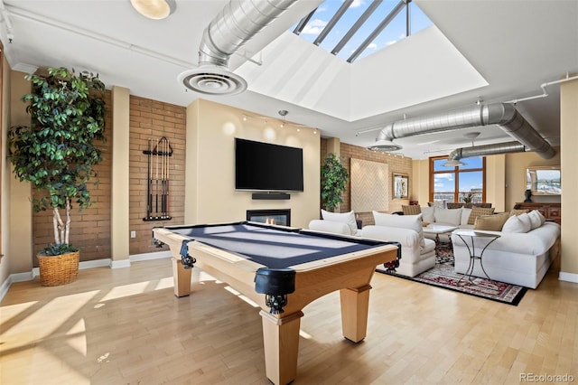 rec room with brick wall, billiards, and light hardwood / wood-style flooring