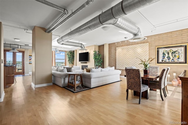 living room featuring brick wall and light hardwood / wood-style floors