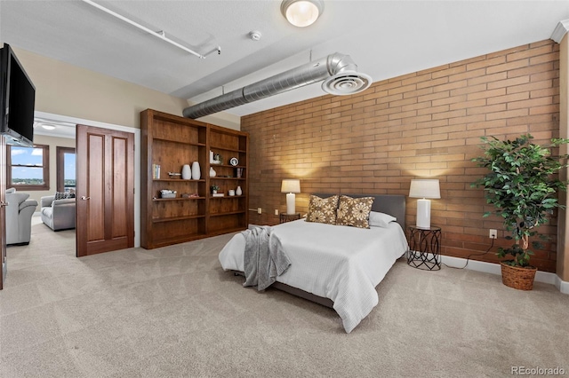 bedroom featuring brick wall and light colored carpet