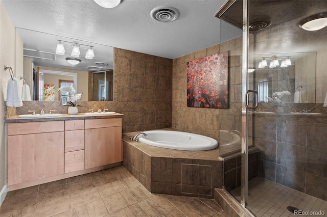 bathroom with a textured ceiling, independent shower and bath, tile patterned flooring, and vanity