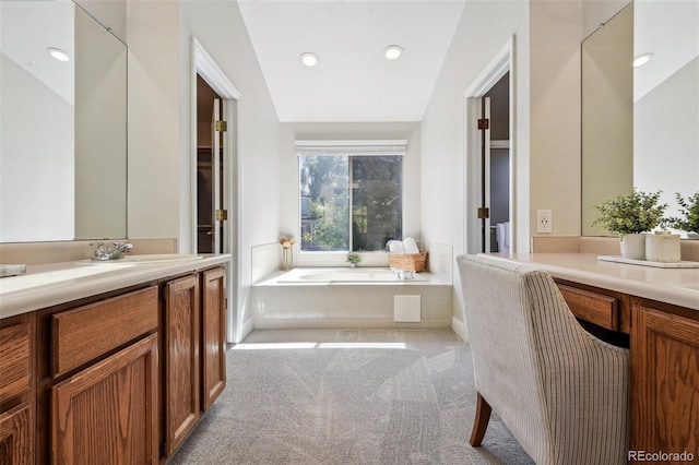 bathroom featuring tiled tub, vanity, and vaulted ceiling