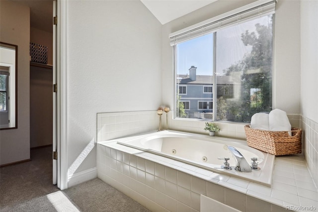 bathroom featuring tiled bath and vaulted ceiling