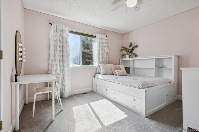 bedroom featuring a textured ceiling, light colored carpet, and ceiling fan