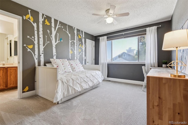 bedroom featuring ceiling fan, light colored carpet, a textured ceiling, and ensuite bath