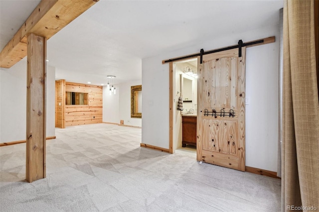 corridor featuring wood walls, a barn door, and light carpet