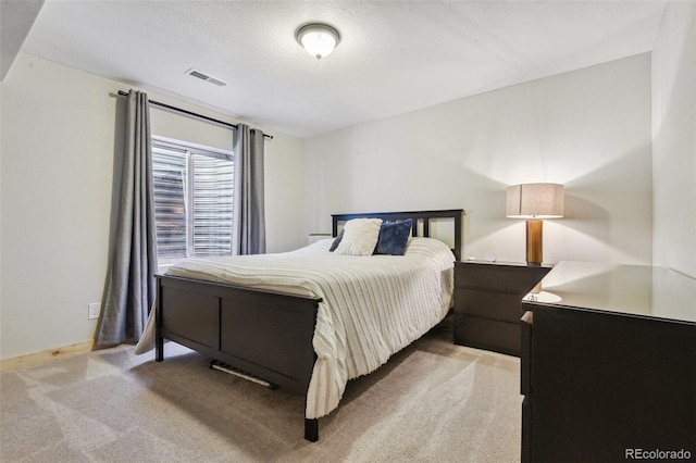 bedroom with light carpet and a textured ceiling