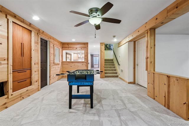 rec room featuring wood walls, ceiling fan, and light colored carpet