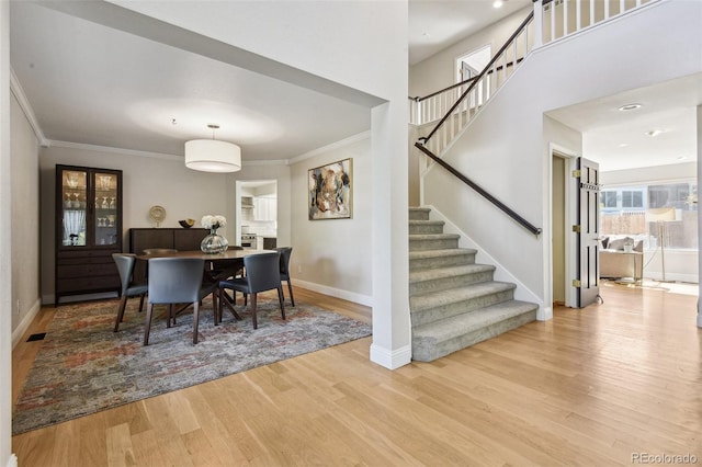 dining room with light wood-type flooring and crown molding