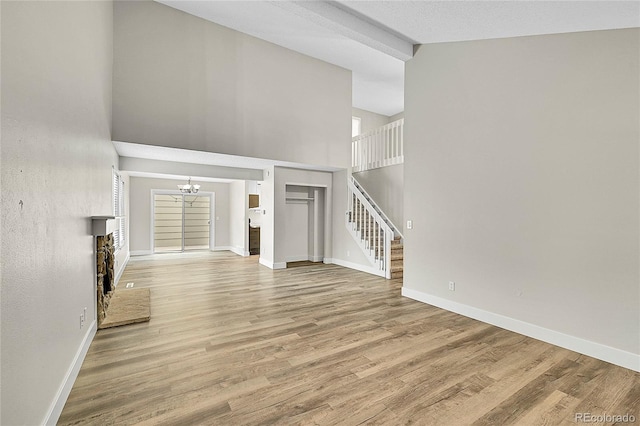 3890 S Atchison Way Unit B, Aurora, CO 80014 - unfurnished living room featuring stairs, high vaulted ceiling, a chandelier, light wood-type flooring, and a fireplace