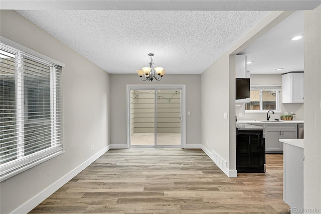 3890 S Atchison Way Unit B, Aurora, CO 80014 - unfurnished dining area with a chandelier, light wood-style flooring, a textured ceiling, and recessed lighting