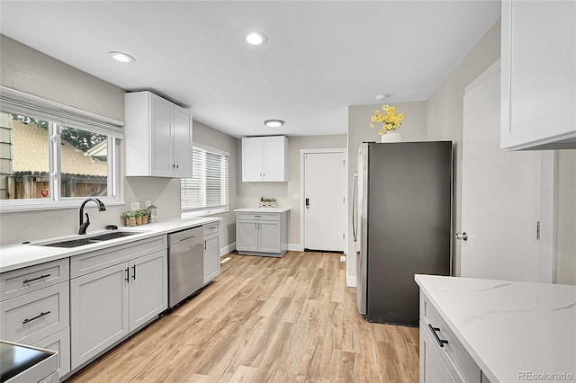 3890 S Atchison Way Unit B, Aurora, CO 80014 - kitchen featuring appliances with stainless steel finishes, light wood finished floors, healthy amount of natural light, recessed lighting, and light stone counters