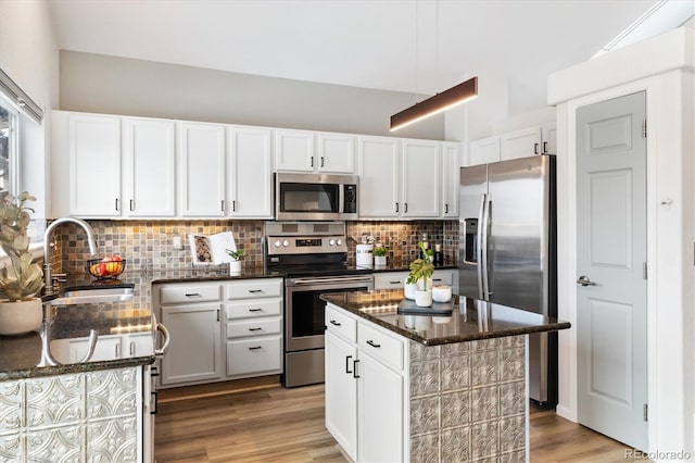 kitchen featuring stainless steel appliances, a sink, white cabinetry, and a center island