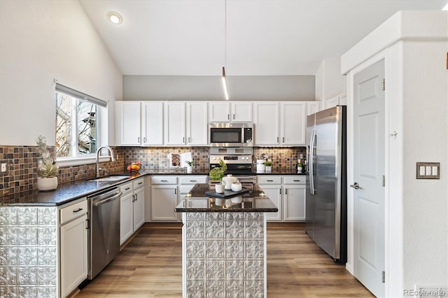 kitchen featuring appliances with stainless steel finishes, white cabinets, a sink, and a center island