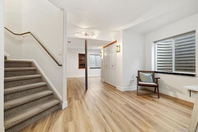 interior space featuring light wood finished floors, stairway, and baseboards