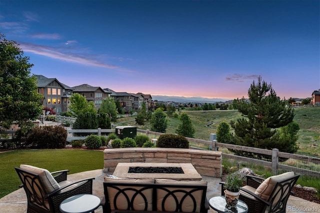 patio terrace at dusk featuring an outdoor fire pit and a yard