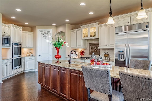 kitchen featuring white cabinets, tasteful backsplash, hanging light fixtures, and built in appliances