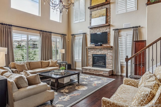 living room with a high ceiling, dark hardwood / wood-style flooring, an inviting chandelier, and a fireplace