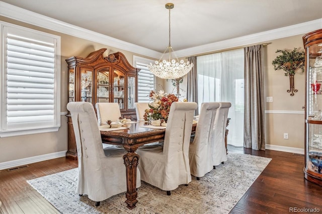 dining area featuring dark hardwood / wood-style flooring, crown molding, and a notable chandelier