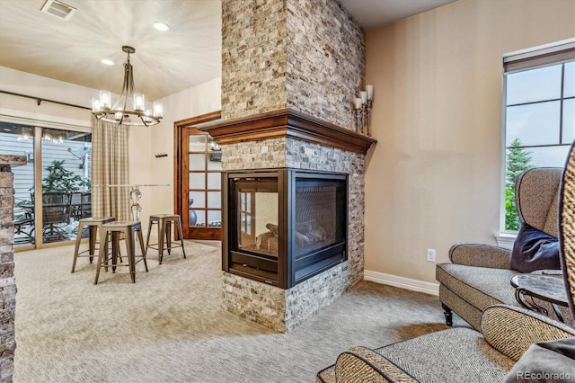 living room featuring carpet, a fireplace, and an inviting chandelier