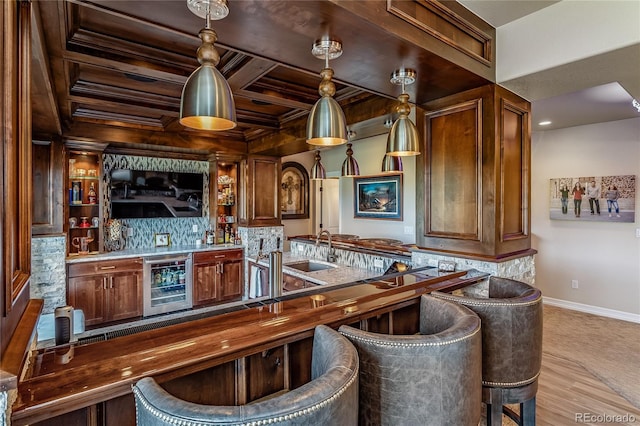 bar with coffered ceiling, decorative backsplash, light wood-type flooring, wine cooler, and sink