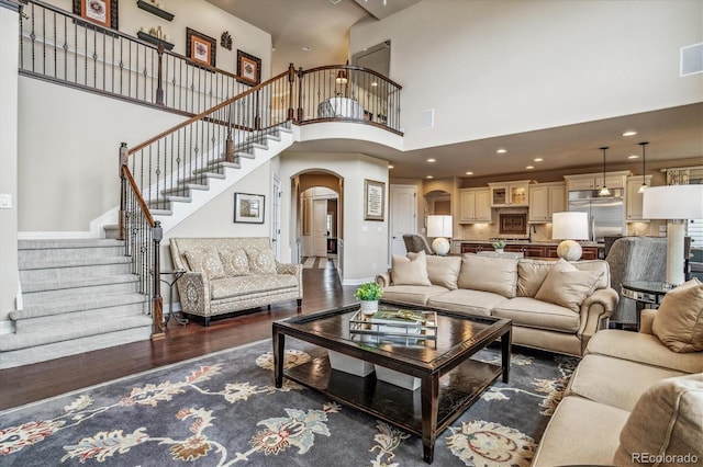 living room featuring a towering ceiling and dark hardwood / wood-style floors