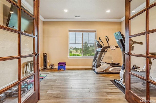 exercise room with crown molding and light wood-type flooring