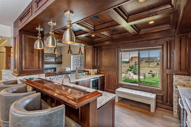 bar with light stone countertops, decorative light fixtures, ornamental molding, wooden ceiling, and coffered ceiling