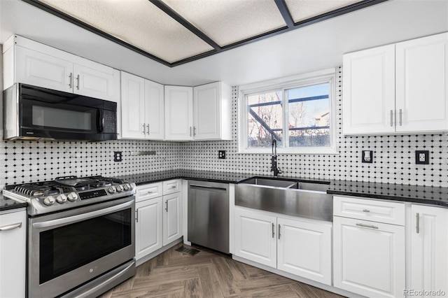 kitchen with white cabinets, dark parquet flooring, stainless steel appliances, and tasteful backsplash