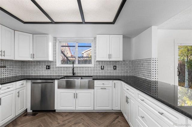 kitchen with dark stone counters, a healthy amount of sunlight, white cabinets, and stainless steel dishwasher