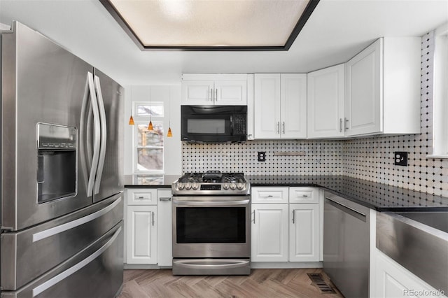 kitchen with white cabinets, appliances with stainless steel finishes, tasteful backsplash, and light parquet floors