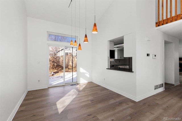 unfurnished living room featuring hardwood / wood-style floors and a high ceiling