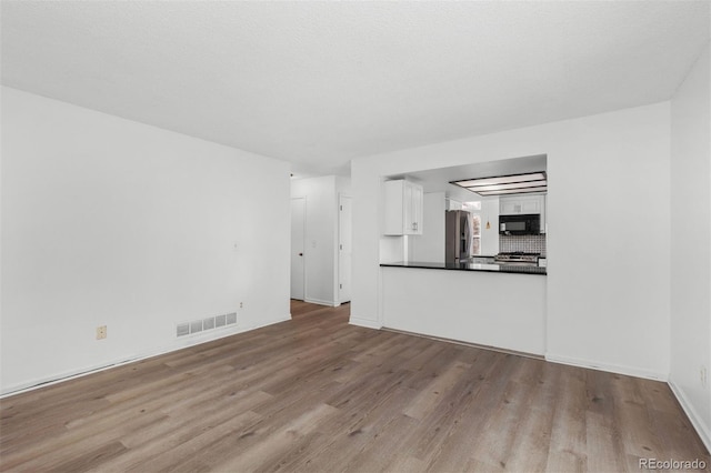 unfurnished living room with light hardwood / wood-style floors and a textured ceiling